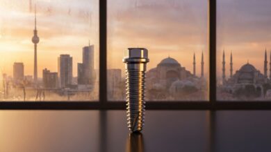 Un implant dentaire en titane de haute technologie au premier plan, avec en arrière-plan flou une vue panoramique fusionnant les horizons de l'Allemagne et d'Istanbul en Turquie, symbolisant le tourisme dentaire.